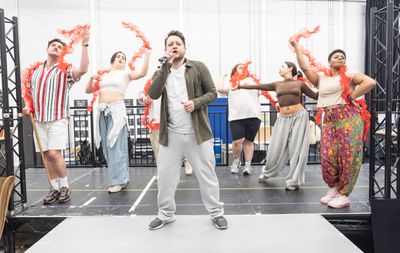 Sam Lupton (Centre) & The cast in rehearsals for BANK OF DAVE, credit Marc Brenner Photo