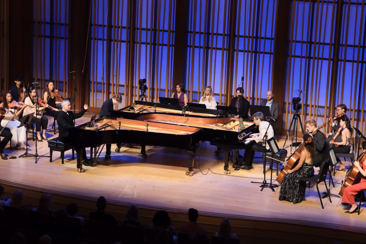 Three pianos on stage amidst other musicians