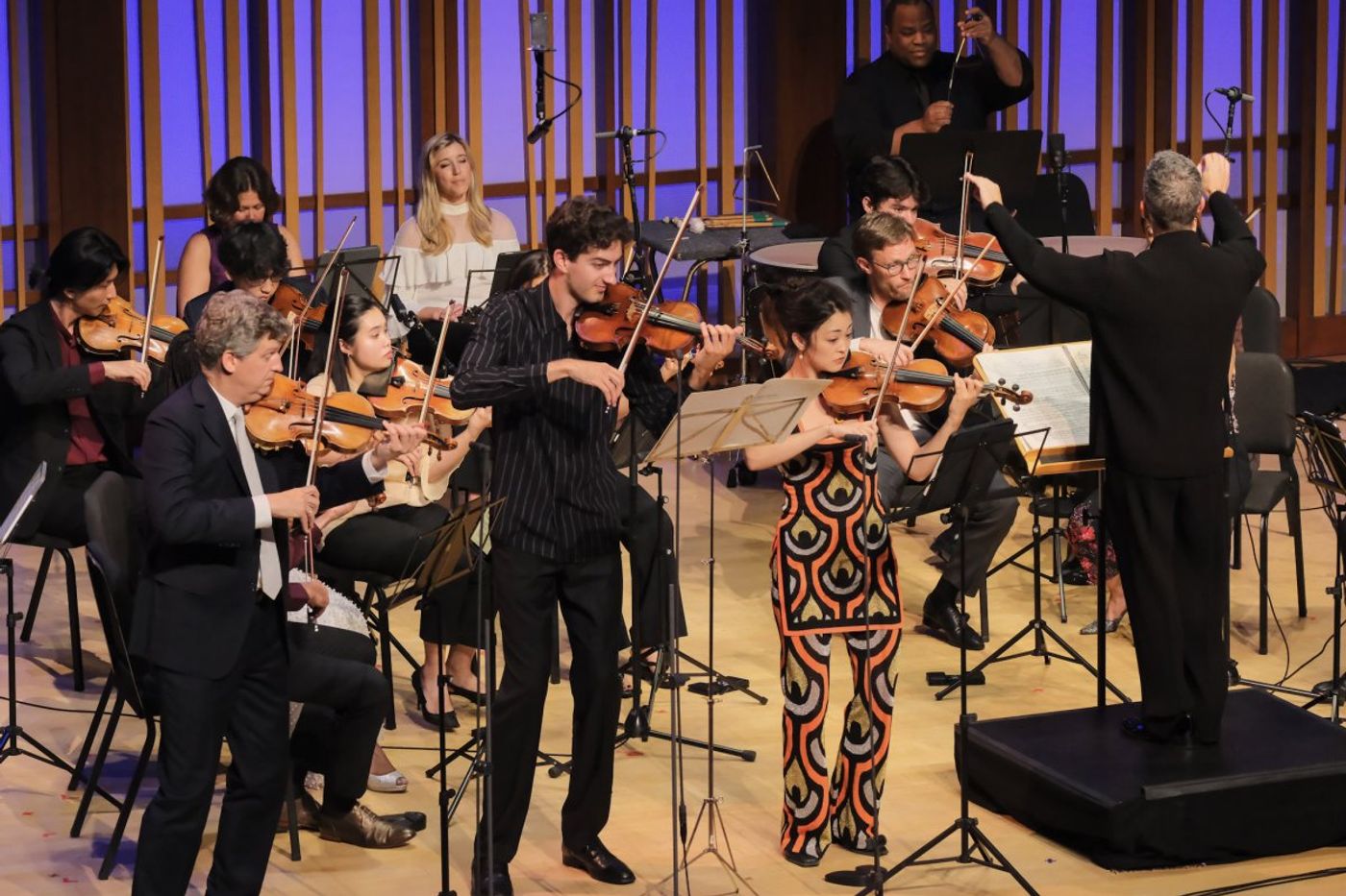 Three violinists in front of chamber orchestra