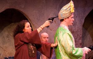 Ambara (Suehyla El-Attar) holds British Lieutenant Douglas Duff (Joe Knezevich) at gun point as Hajj Waleed (Tom Thon, background) watches. @ BroadwayWorld Ambara (Suehyla El-Attar) holds British Lieutenant Douglas Duff (Joe Knezevich) at gu Photo