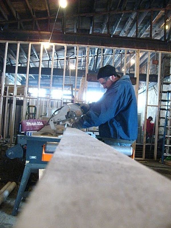 Josh Kessler cuts a piece of lumber for wall framing Photo