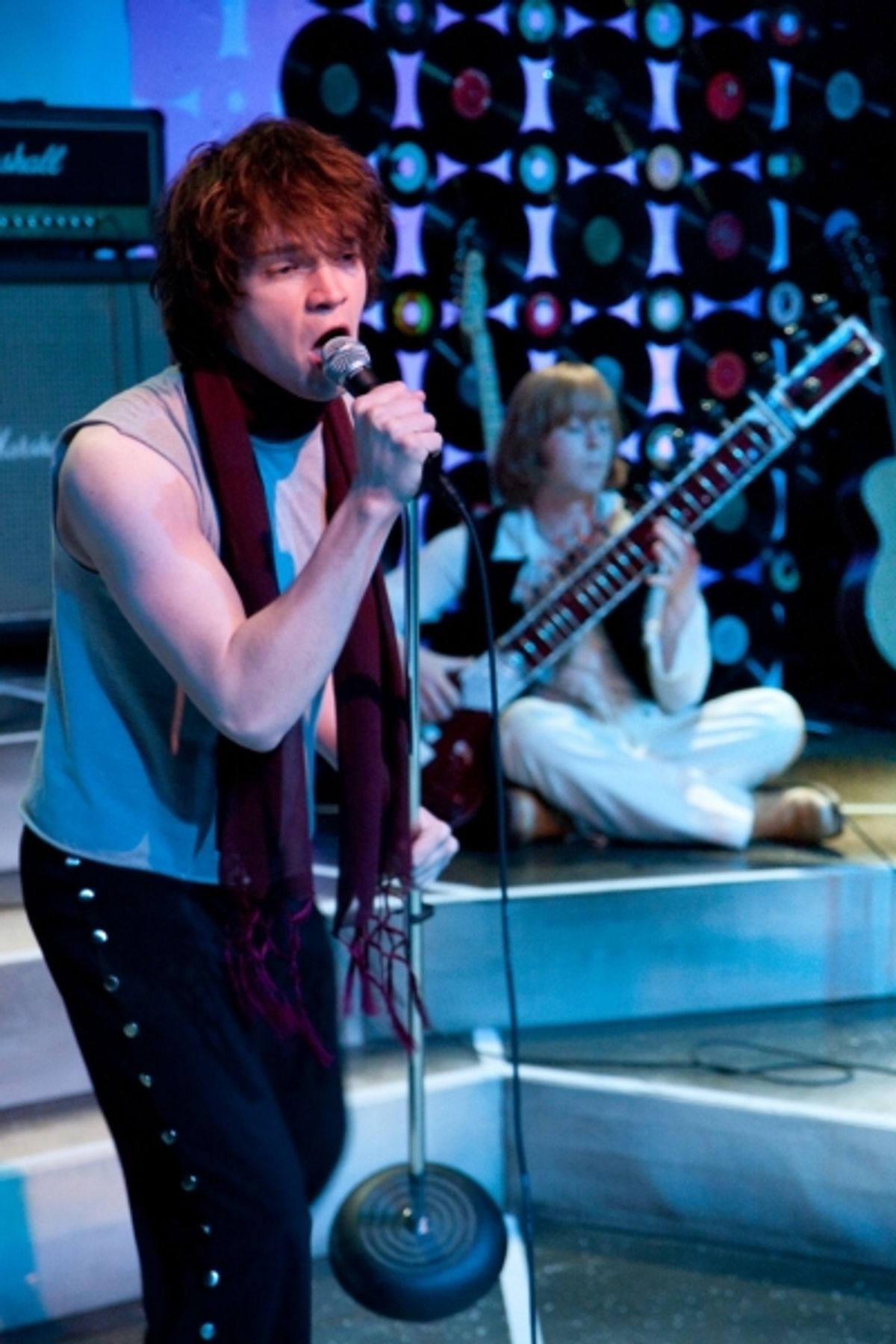 Mick (Nick Vidal) sings while Brian (AaRon Snook) plays the sitar at 