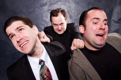 The commissioner (Eric Paskey) and Sporty (Anthony Tournis) are pushed toward a windo Photo