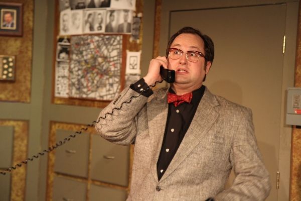 The Madman (Joseph Stearns) impersonates a police officer on the phone Photo