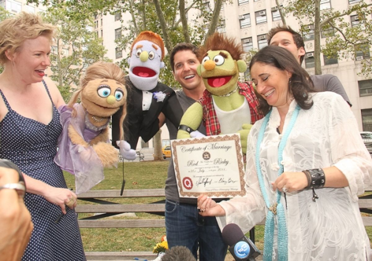 The official marriage certificate is presented to the puppets by Amy Hausman of the Starlight Rainbow Wedding Initiative at 