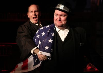 J. Edgar Hoover (E.J. Subkoviak) is wrapped in an American flag by the narrator (Jake Photo