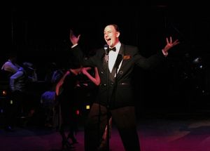 Nate Bomberg (Jake Endres) welcomes the audience to the Hollyhocks night club with a  Photo