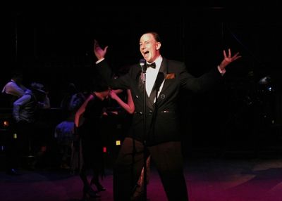 Nate Bomberg (Jake Endres) welcomes the audience to the Hollyhocks night club with a  Photo